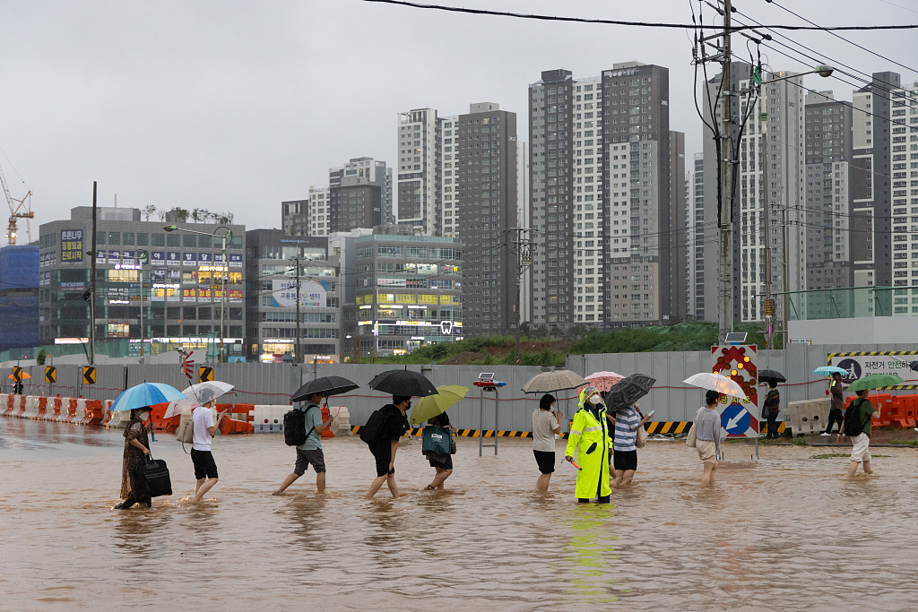 Pedestrians are escorted across a flooded road in Gimpo City, South Korea, on Aug. 9, 2022. At least eight people were killed after the heaviest flood in 80 years hit Seoul, inundating streets and subway stations and causing blackouts. /VCG
