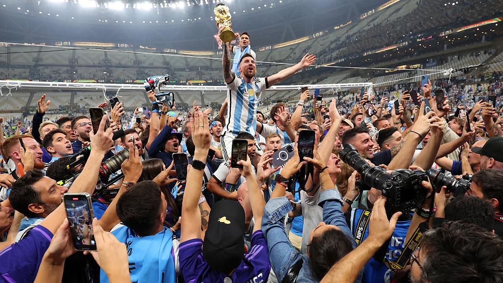 Argentinian footballer Lionel Messi celebrates on footballer Sergio Aguero's shoulders with the FIFA World Cup Trophy following his team's victory in the FIFA World Cup Qatar 2022 Final match between Argentina and France at Lusail Stadium in Lusail City, Qatar, December 18, 2022. /CFP