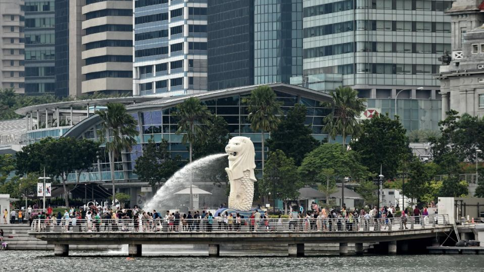 Tourists gather on a jetty around the Merlion next to the financial business district in Singapore. /AFP