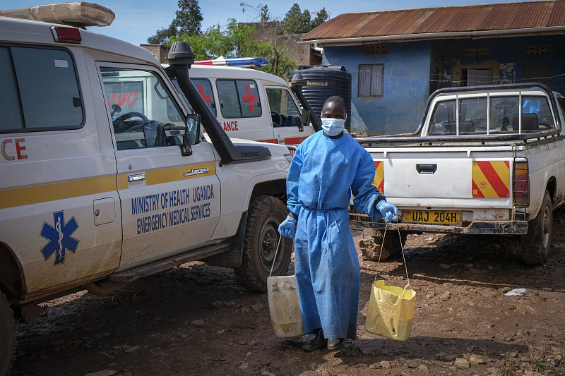 A man wearing protective clothing carries water to wash the interior of an ambulance used to transport suspected Ebola victims, in the town of Kassanda in Uganda, November 1, 2022.