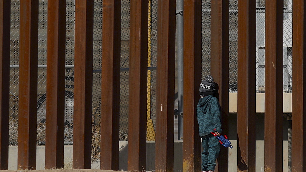 Venezuelan migrant George, 5, stands by the bars of the border wall holding a Captain America action figure while staying with his family on the Rio Grande river in Ciudad Juarez, Chihuahua state, Mexico, December 27, 2022. /CFP