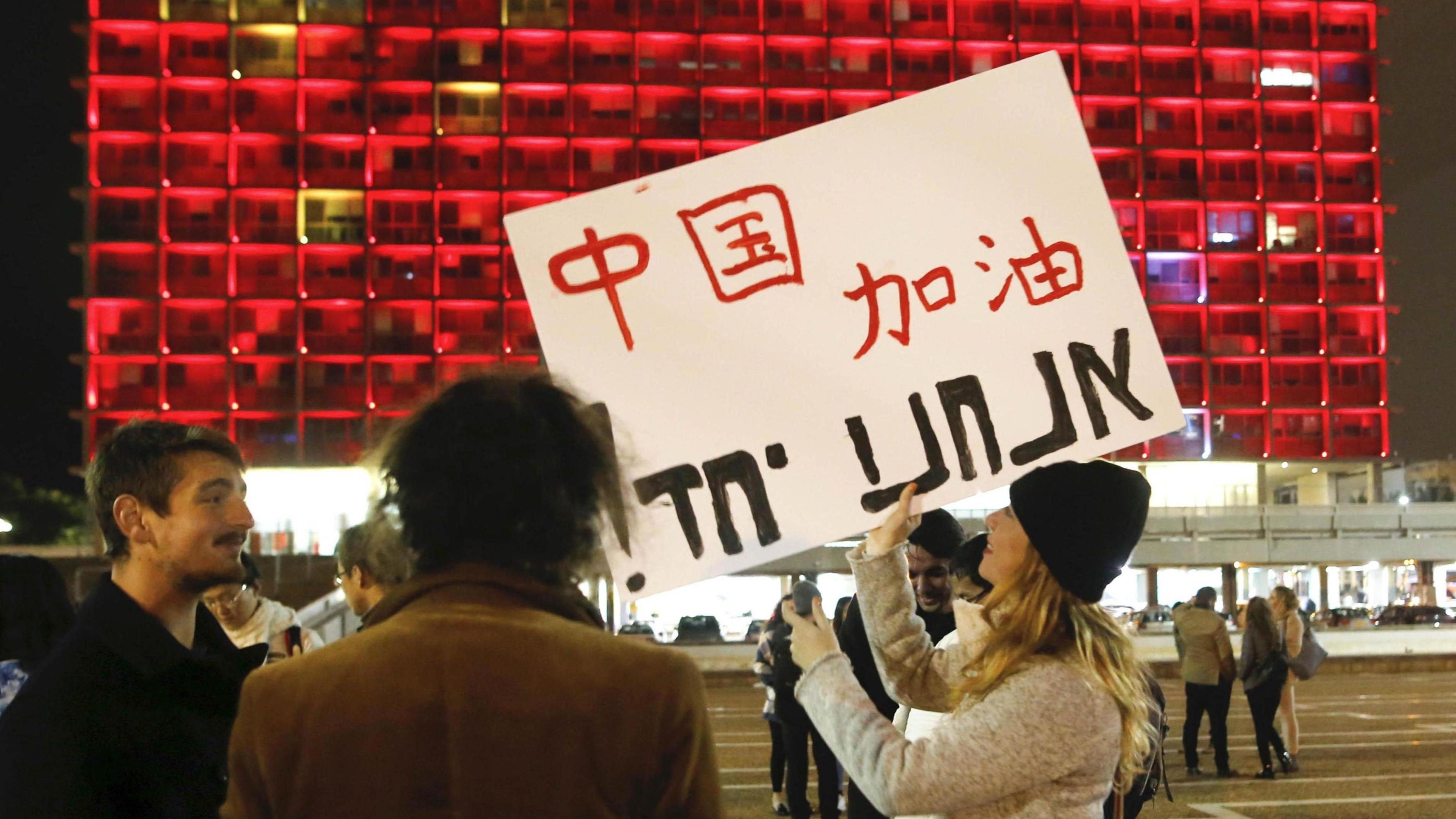 A woman holds a placard in front of the Tel Aviv Municipality Hall to show her support for China's fight against COVID-19, Tel Aviv, Israel, February 11, 2020. /Xinhua
