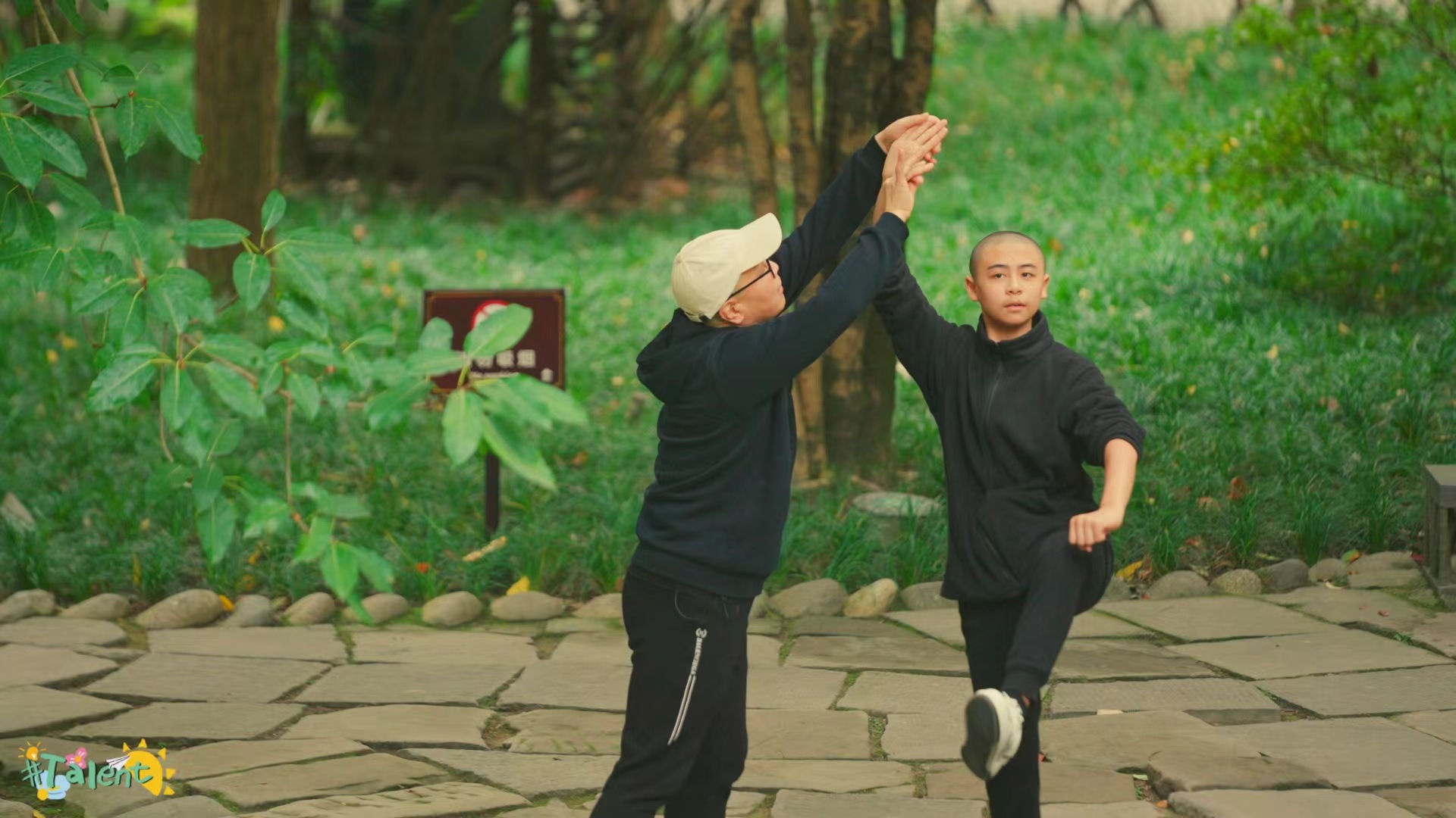 Hu Yibo practices Sichuan Opera movements with his grandfather in a park in Chengdu, Sichuan Province, China. /CGTN
