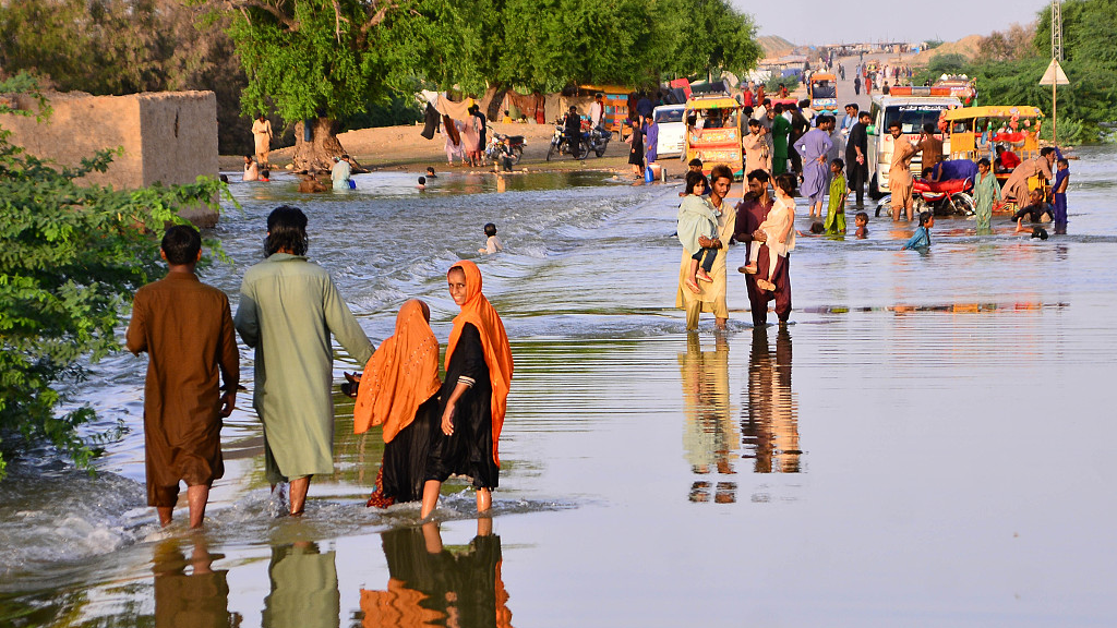 People wade through a flooded area in Sewan Sharif, Pakistan's southern Sindh Province, September 6, 2022. /CFP