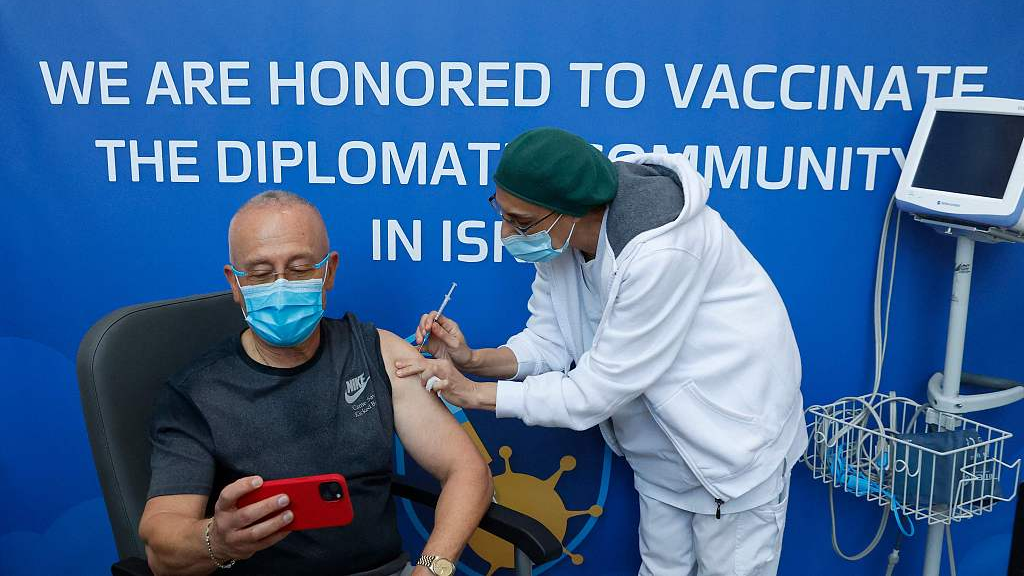 A senior holds a phone while receiving a fourth dose of the Pfizer-BioNTech COVID-19 vaccine at Ichilov Tel Aviv Sourasky Medical Center in Israel's Mediterranean coastal city of Tel Aviv, January 3, 2022. /CFP