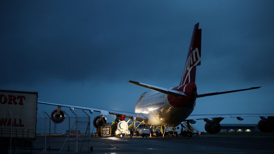 Technicians work on Virgin Orbit's LauncherOne rocket, attached to the wing of Cosmic Girl, a Boeing 747-400 aircraft, ahead of launch, at Spaceport Cornwall at Newquay Airport in Newquay, Britain, January 8, 2023. /Reuters