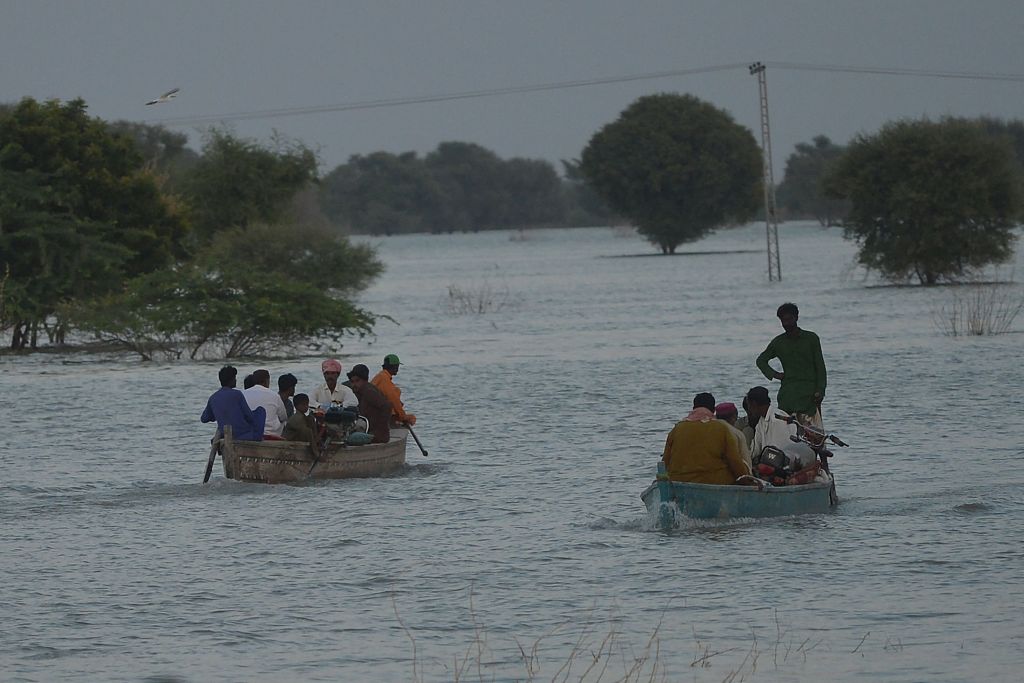 Displaced people use boats to cross the flooded area in Dadu district, Sindh province, Pakistan, September 27, 2022. /CFP