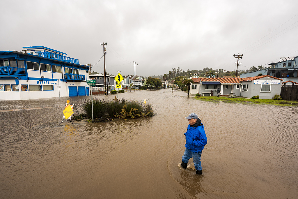 A pedestrian wades through a flooded neighborhood in Aptos, California, US, on Saturday, January 14, 2023. /VCG