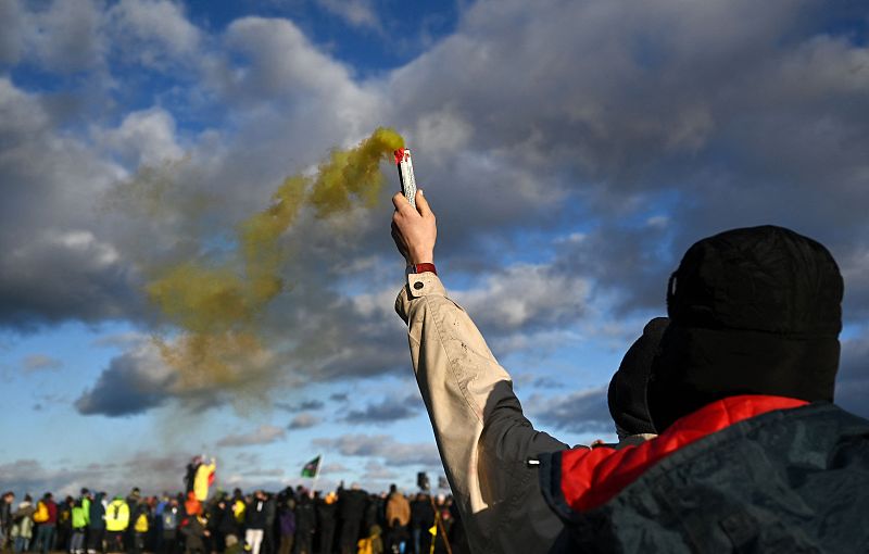 An activist burns a flare at the Garzweiler lignite opencast mine ahead of the imminent clearance of the nearby village of Luetzerath, western Germany，January 8, 2023. /CFP