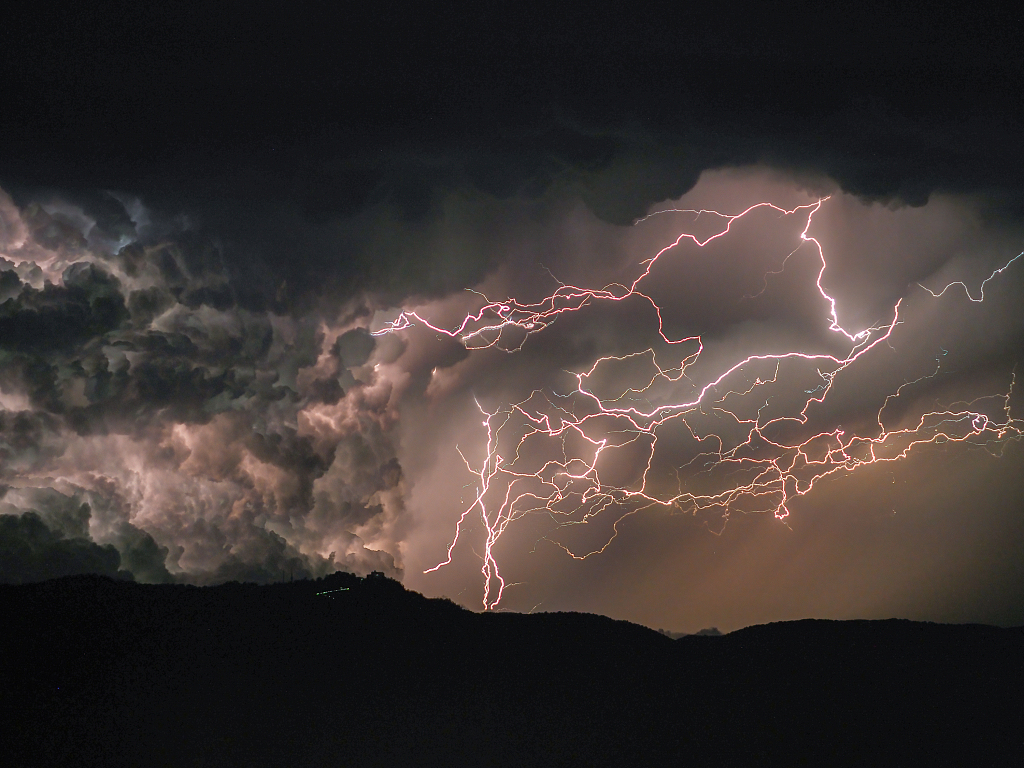A sleepy town is illuminated by a backdrop of spectacular lightning strikes over a mountain range in Spain, June, 2022. /CFP