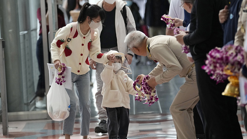 A Thai official gives a garland to Chinese tourists as they arrive at Suvarnabhumi International Airport in Samut Prakarn province, Thailand, Monday, Jan. 9, 2023. /CFP