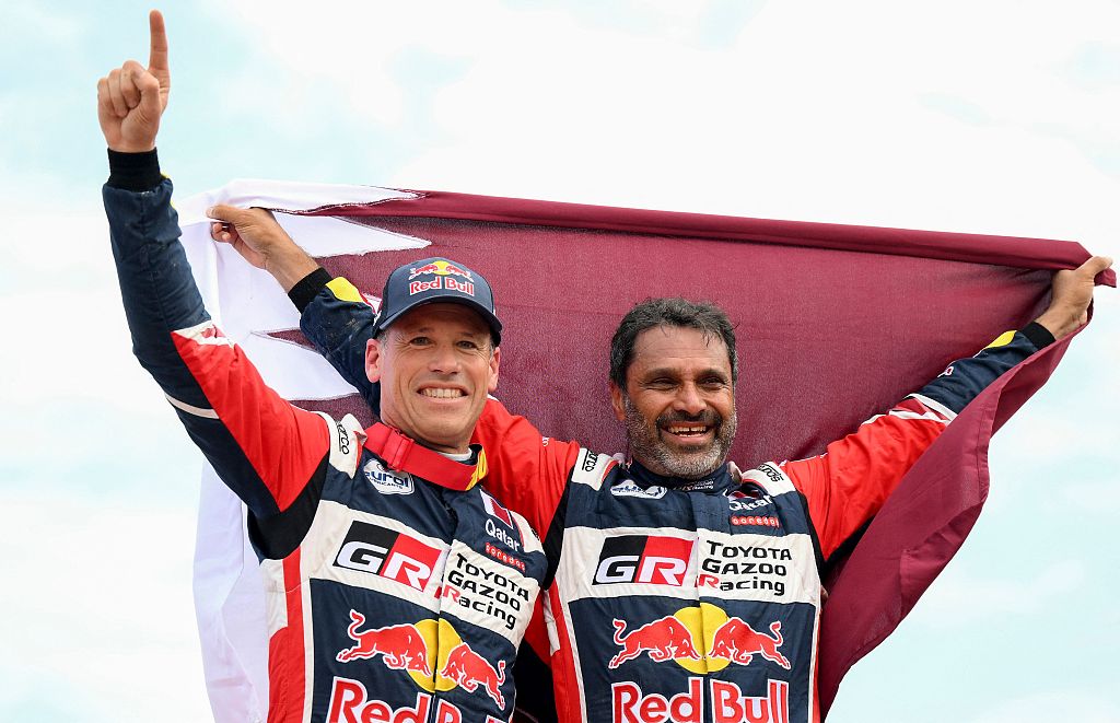 Qatari driver Nasser Al-Attiyah (R) and his co-driver Mathieu Baumel of France, from Toyota Gazoo Racing, celebrate after winning his fifth Dakar Rally driver's title and second in a row, in Dammam, Saudi Arabia, January 15, 2023. /CFP