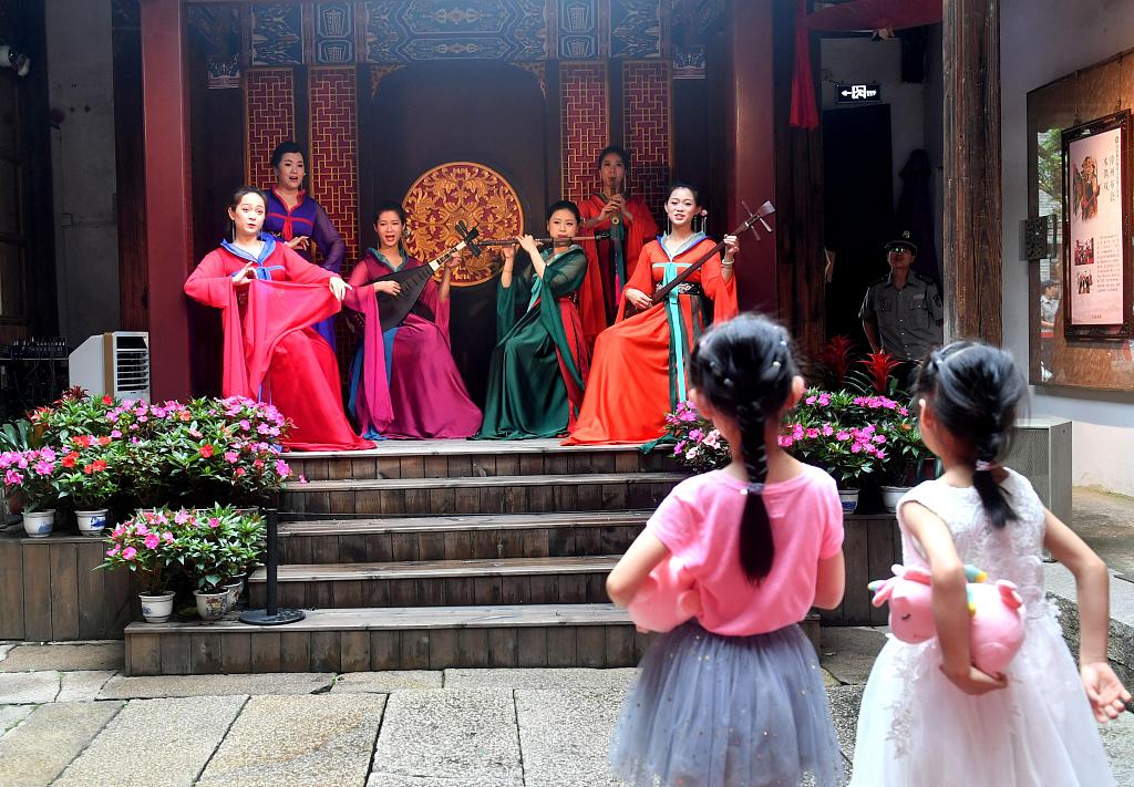 Two little girls are enjoying a performance of Naamyam in Fujian in 2019. /VCG
