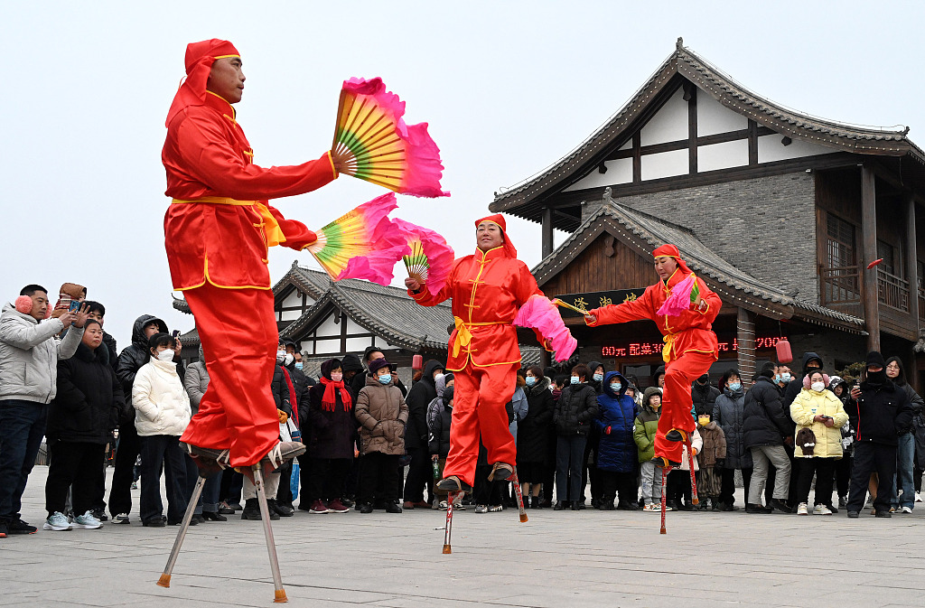 Performers wave fans to keep balance on stilts. /CFP