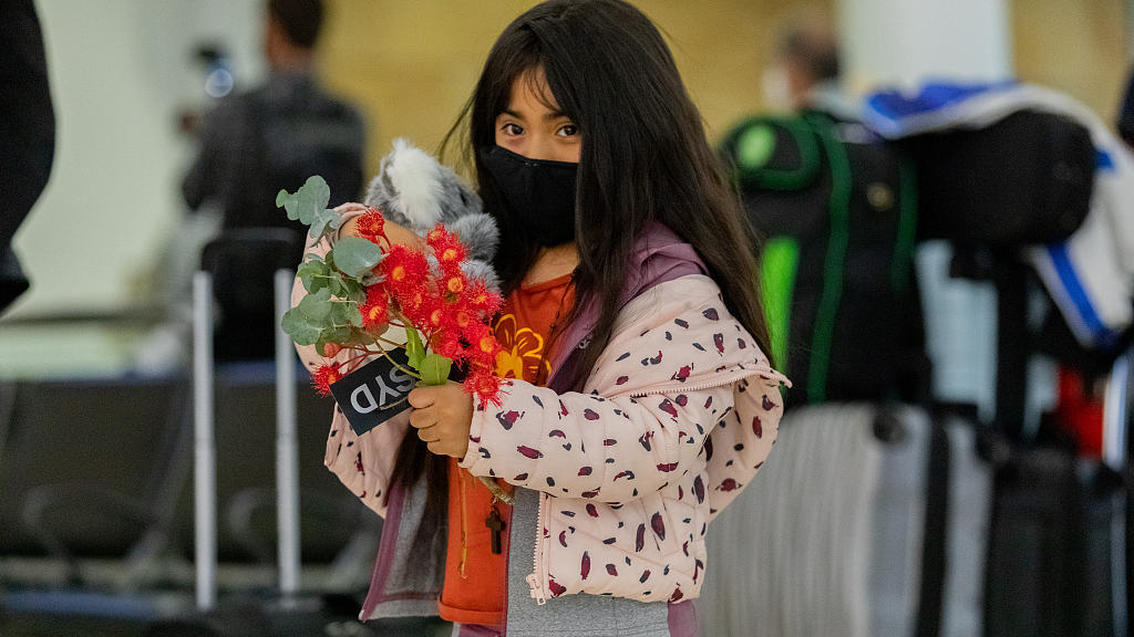 A young girl wearing a mask holds flowers after landing at Sydney International Airport in Sydney, Australia, February 21, 2022 /CFP