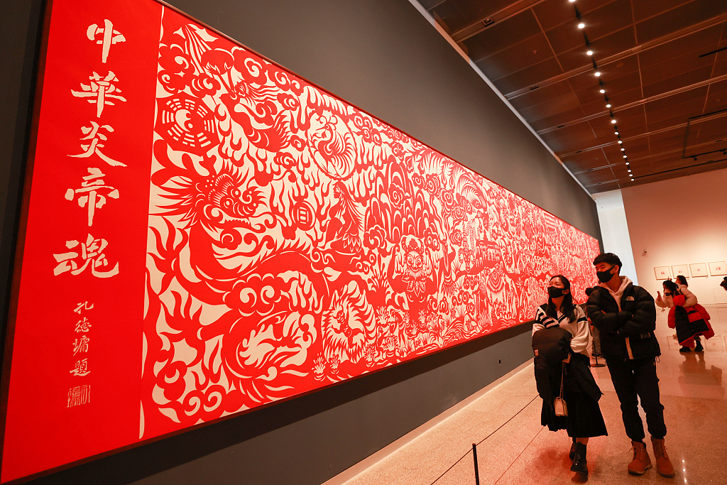 Visitors walk past a huge paper-cut work on display at the China National Arts and Crafts Museum and China Intangible Cultural Heritage Museum in Beijing. /CFP