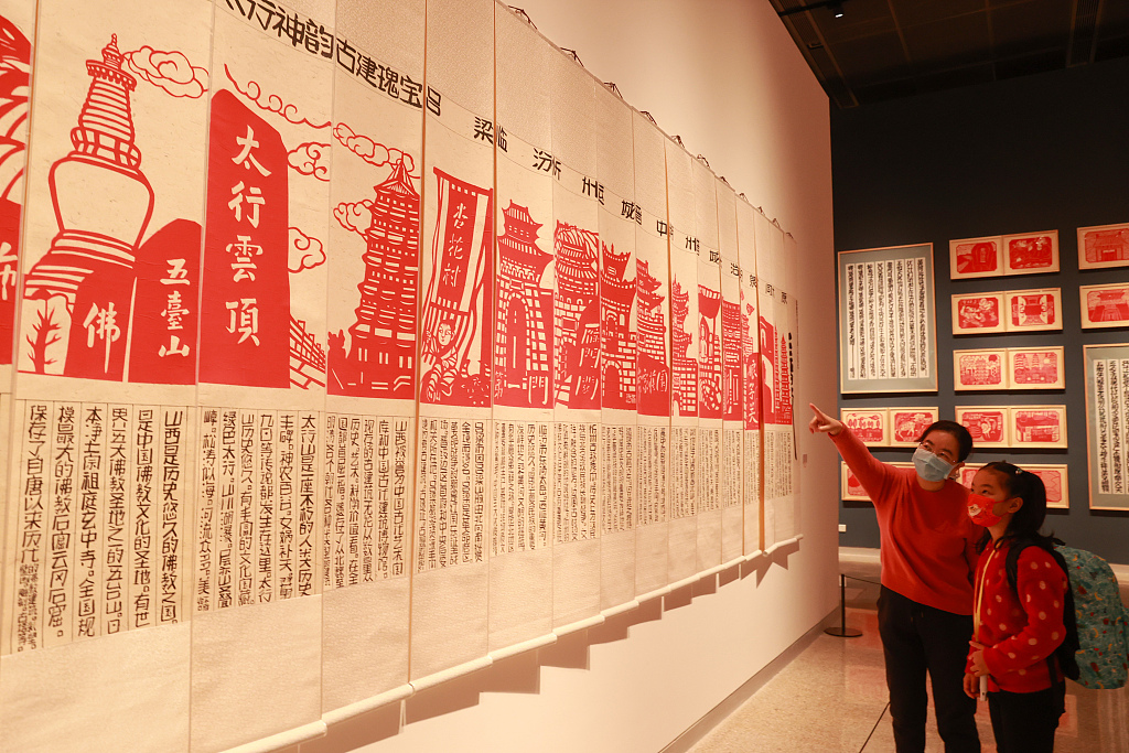 A mother explains paper-cut works to her daughter at the China National Arts and Crafts Museum and China Intangible Cultural Heritage Museum in Beijing. /CFP