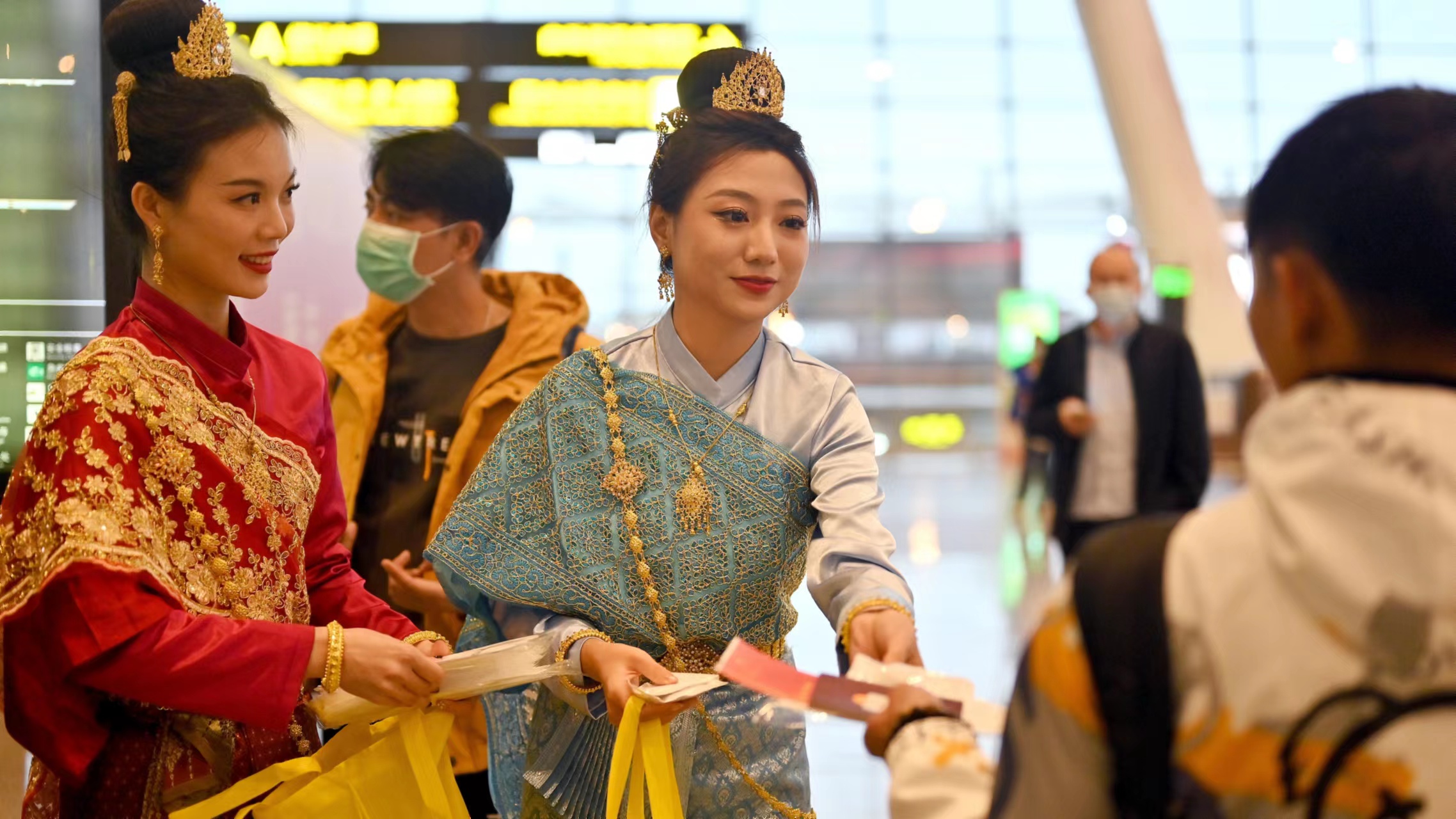 Staff dressed in Thai costumes present souvenirs to the first group of tourists to Thailand in Nanning, capital of Guangxi Zhuang Autonomous Region, China, February 6, 2023. /CFP