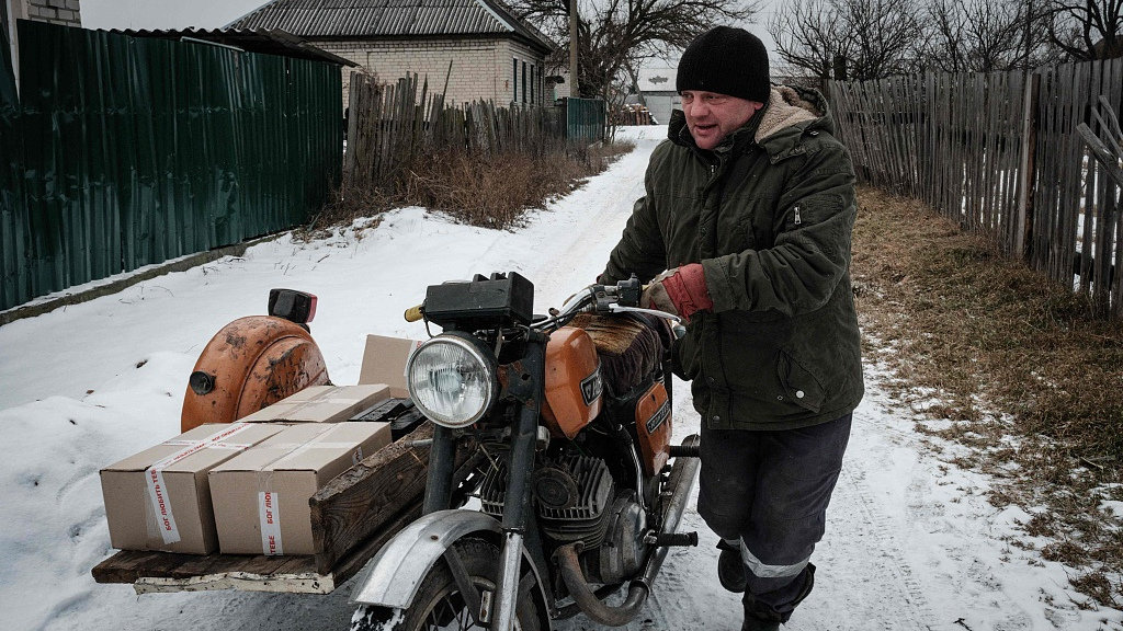 A man pushes a motorcycle transporting food distribution boxes in Yampil, Ukraine, February 6, 2023./CFP