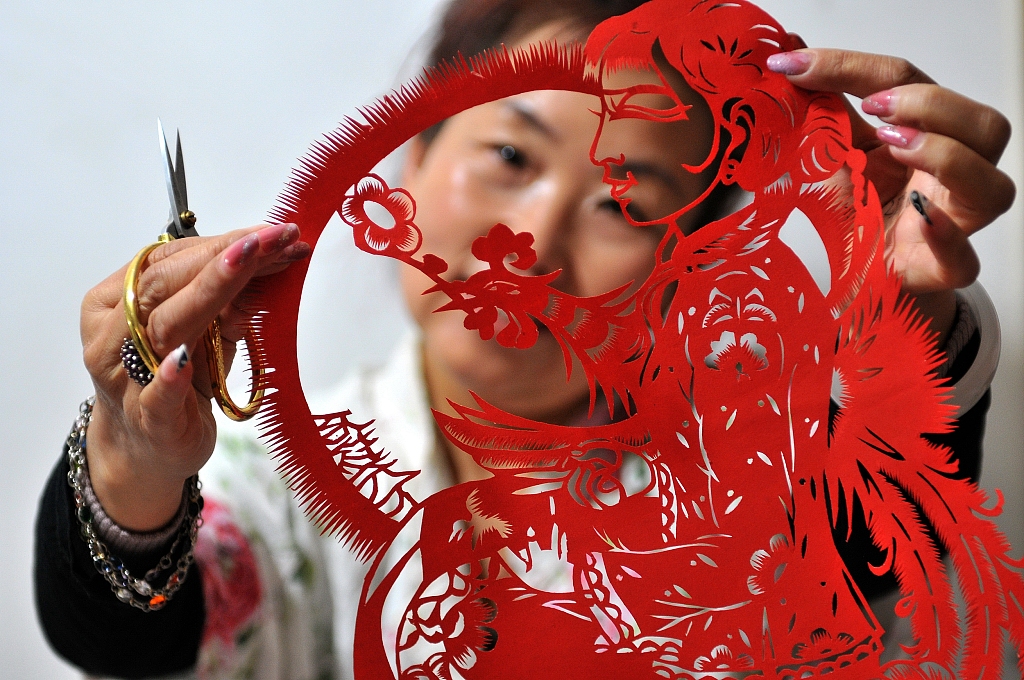 A woman shows her paper cut work with Shaanbei style. /CFP