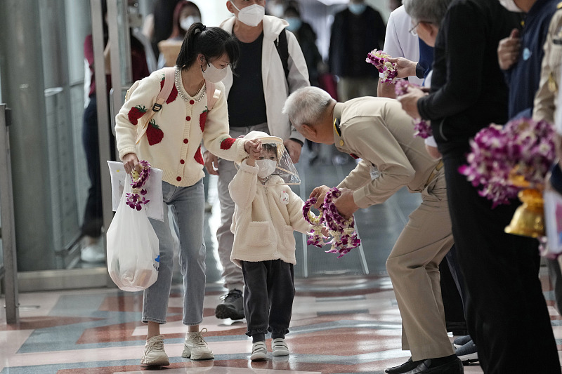 A Thai official gives a garland to Chinese tourists as they arrive at Suvarnabhumi International Airport in Samut Prakarn province, Thailand, Monday, Jan. 9, 2023. /VCG
