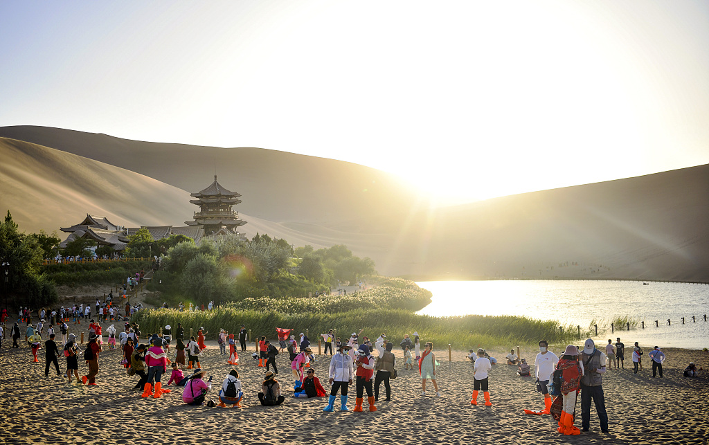 A file photo shows tourists at the Mingsha Mountain and Crescent Moon Spring scenic area in Dunhuang, Gansu. /CFP