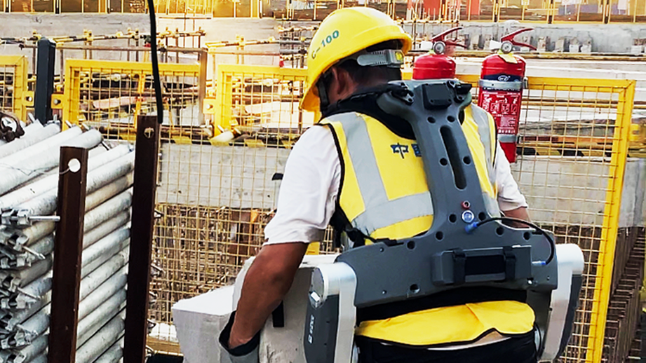 A worker moves a heavy item around at a construction site with assistance of the robotic exoskeleton. /Provided by ULS Robotics