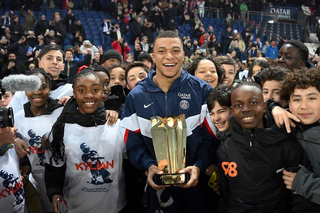 Kylian Mbappe poses with a trophy and children at the end of a ceremony after he became Paris Saint-Germain's all-time top scorer at The Parc des Princes Stadium in Paris, France, March 4, 2023. /CFP