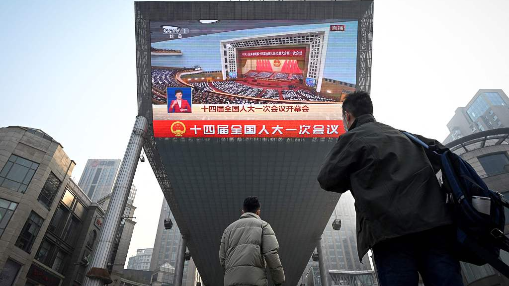 People watch live coverage of first session of the 14th National People's Congress on an outdoor screen in Beijing, China, March 5, 2023. /CFP