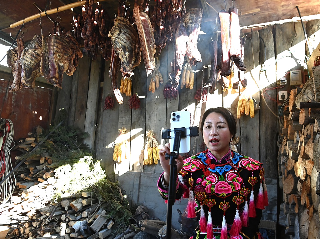 A Qiang woman in ethnic costume sells cured meat on a livestream platform. /CFP