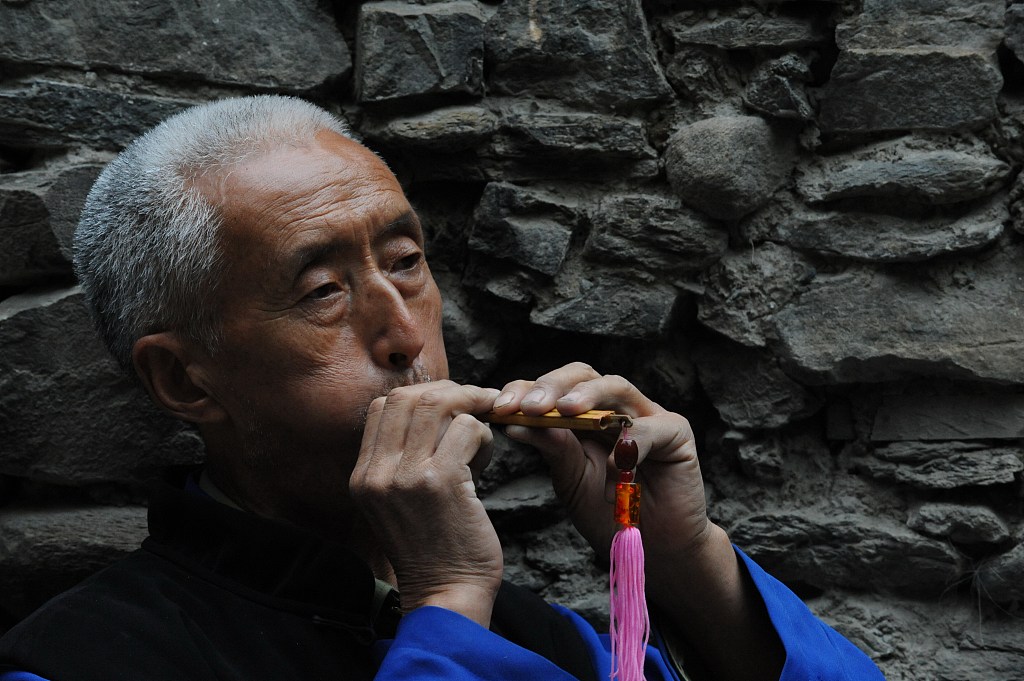 An elderly man plays the qiangdi, a traditional Chinese flute, at Taoping Village in Wenchuan County, Sichuan. /CFP
