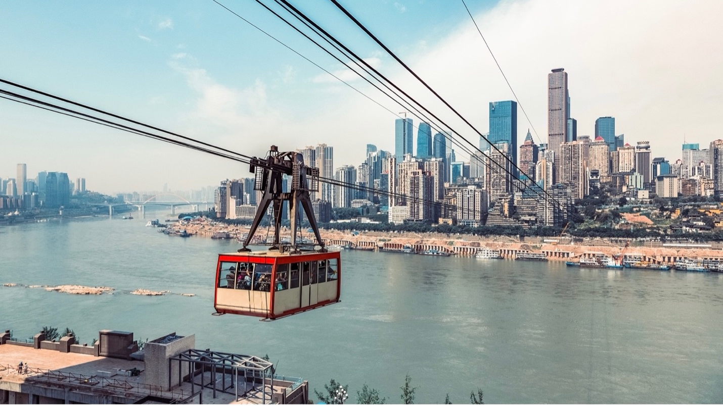 Riding a cable car is a unique way to see the gorgeous scenery on both sides of the Yangtze River in Chongqing City, China. / VCG