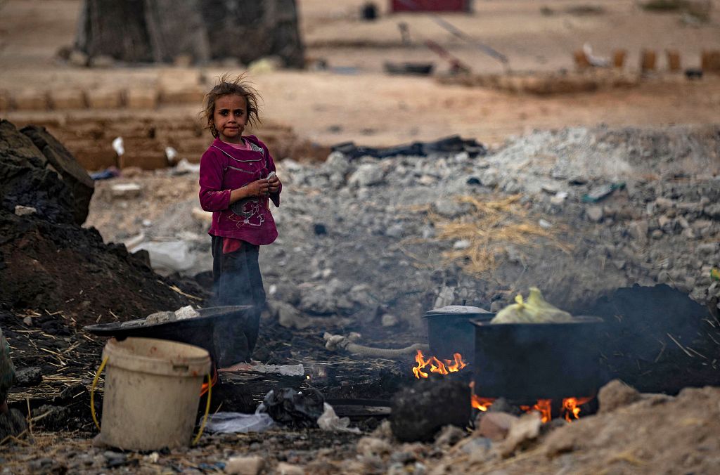 A girl stands near cooking pots placed on fire in the countryside of Raqa in northern Syria, November 7, 2022. /CFP