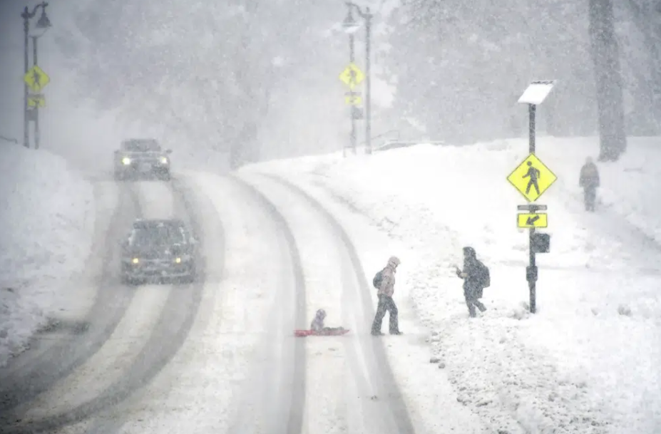 Pedestrians crosses Main Street in Williamstown, Massachusetts during a snowstorm, March 14 2023. /AP