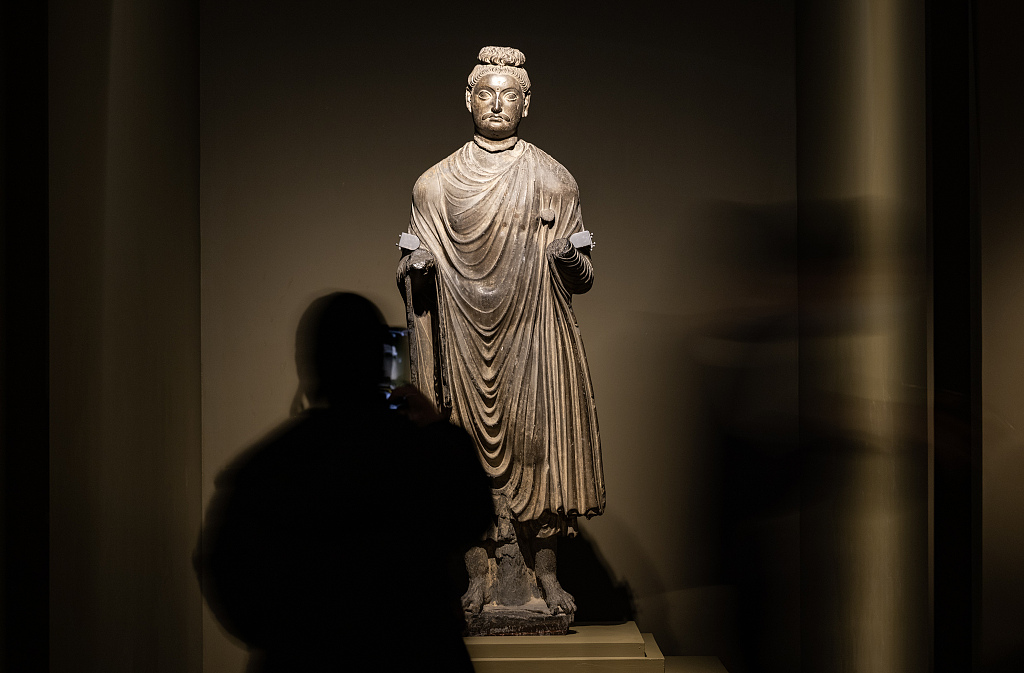 A visitor takes a photo of a life-sized statue at the 'Gandhara Heritage Along the Silk Road' exhibition held at the Palace Museum, Beijing. /CFP