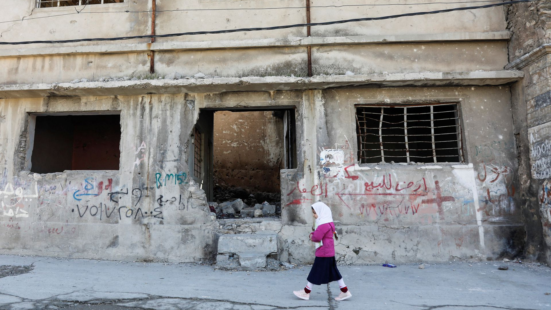 A girl walks near a building destroyed during past fighting with Islamic State militants in the old city of Mosul, Iraq, February 1, 2022. /Reuters