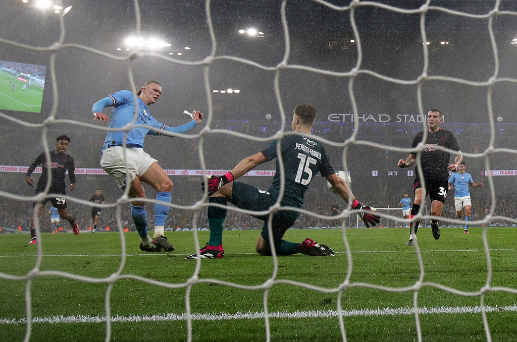 Erling Haaland of Manchester City rolls the ball past goalkeeper Bailey Peacock-Farrell of Burnley during their FA Cup clash at Etihad Stadium in Manchester, England, March 18, 2023. /CFP