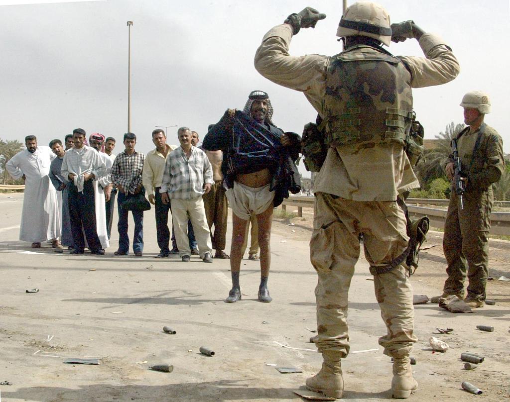 A U.S. soldier orders a tribesman to lift his robe, fearing suicide bombers, on al-Durra highway, Baghdad, Iraq, April 10, 2003. /CFP