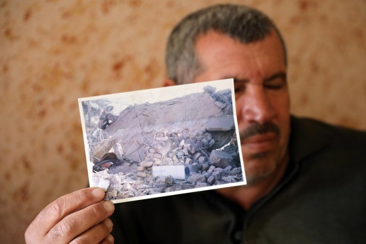 Abdullah Ibrahim shows a photo of his house destroyed by a reckless U.S. missile, which also left him disabled, in Salahudin province, Iraq, January 4, 2022. /Xinhua