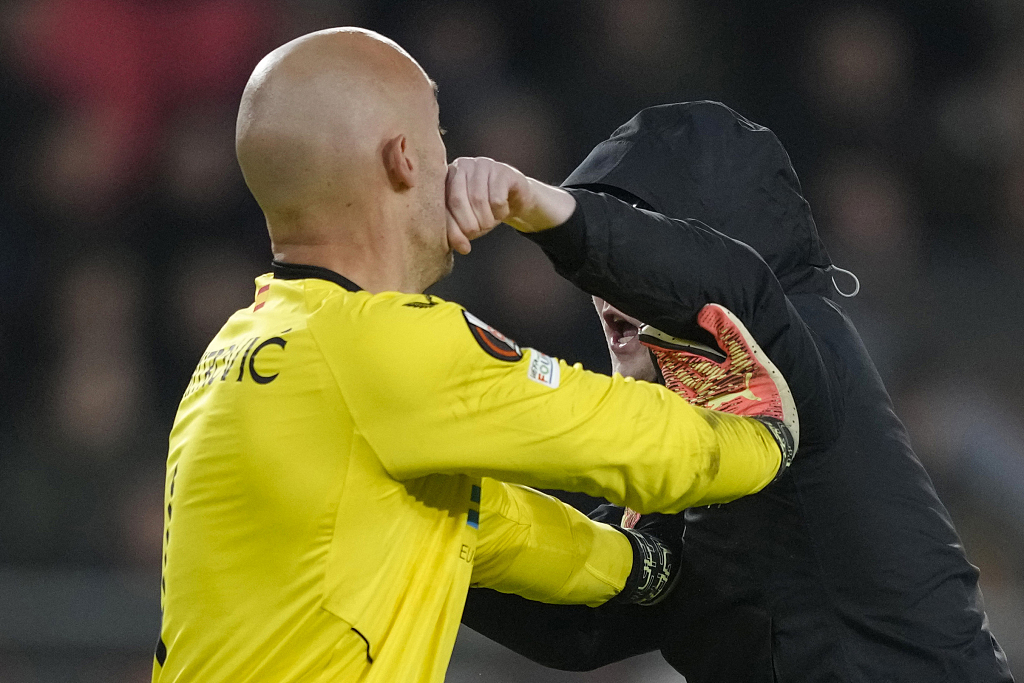 A man attacks Marko Dmitrovic (L), goalkeeper of Sevilla, during the second leg game of the UEFA Europa League knockout round play-off at the Philips Stadion in Eindhoven, the Netherlands, February 23, 2023. /CFP