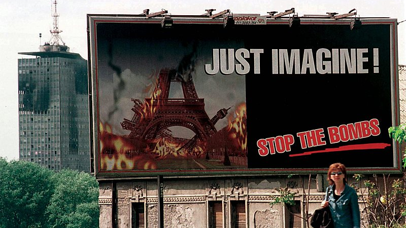 A street poster is displayed, calling for the stop of NATO bombing, with a bombed building in the background in Belgrade, Serbia, May, 1999. /CFP
