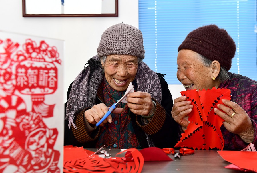 Two elderly women chat with each other while making paper-cuts at a care center for the elderly in Huangjiayu Village, Rizhao, east China's Shandong Province, February 27, 2022. /Xinhua