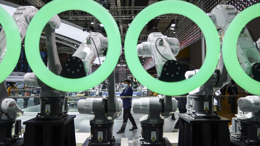 A visitor walks past industrial robots of Nachi company from Japan at the Intelligent Industry and Information Technology exhibition area during the third China International Import Expo in Shanghai, east China, November 9, 2020. /Xinhua