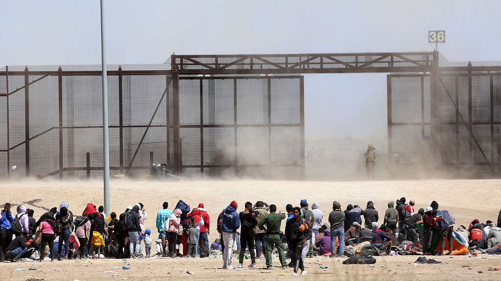 Migrants from Mexico wait next to the U.S. border wall where U.S. Border Patrol agents stand guard in Ciudad Juarez, Mexico, March 30, 2023. /CFP