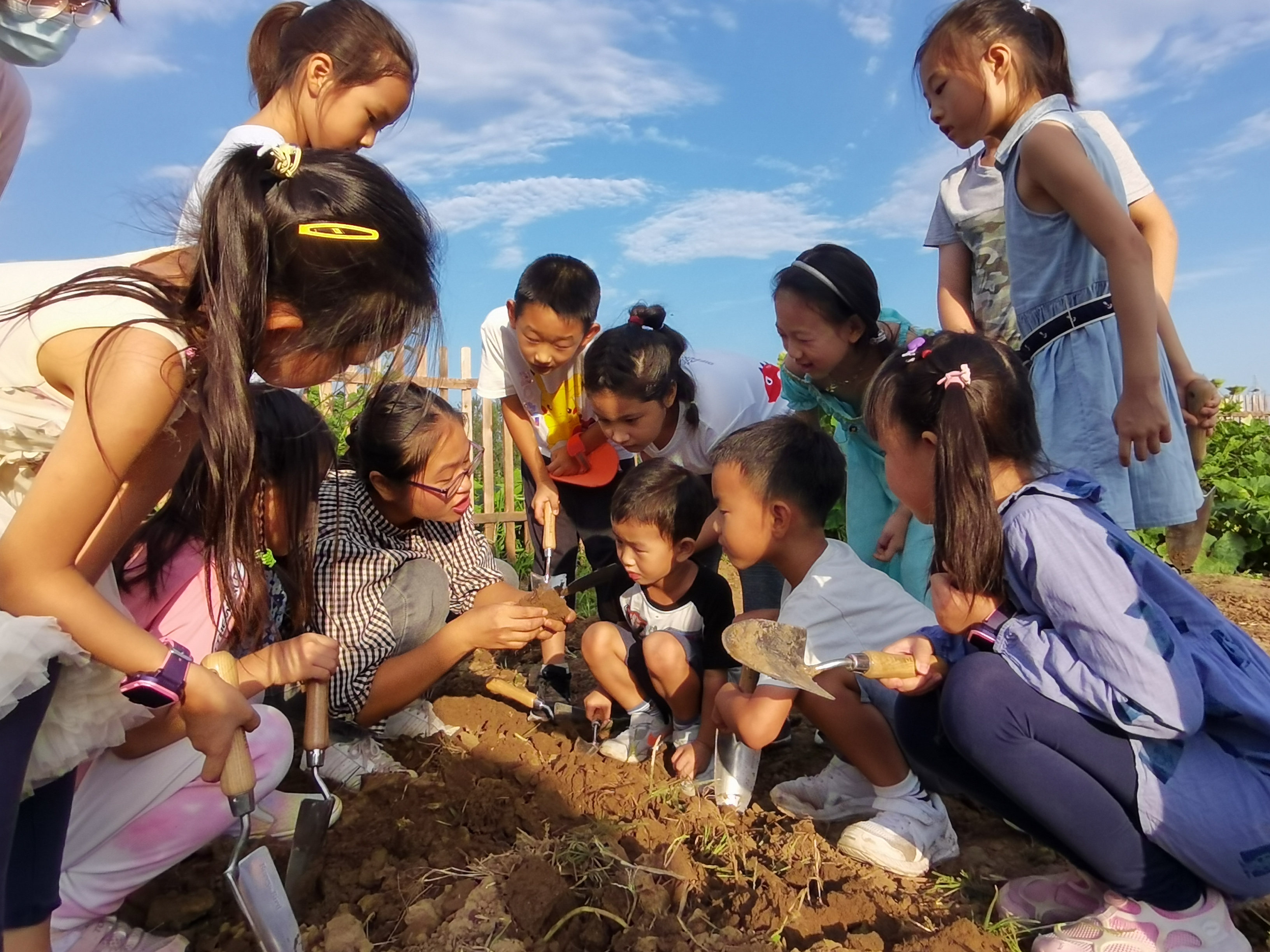 A young employee of the farm Wang Chunhua explains knowledge of soil for children who come from downtown Beijing during a field activity, Beijing, China, June, 2022. /Shared Harvest
