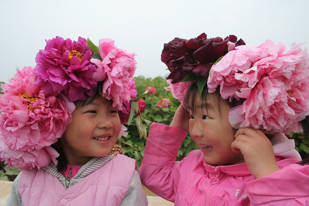 Children wear peony flower crowns at Caozhou Peony Garden, Heze, Shandong. /CFP