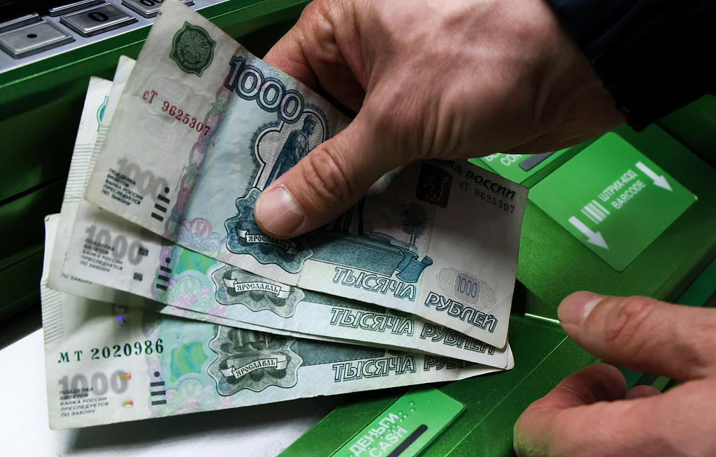 A person holds cash withdrawn from an ATM machine at a Sberbank branch in Russia, February 28, 2022. /CFP
