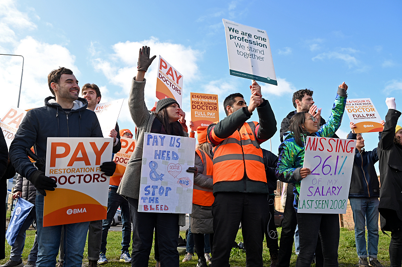 Junior doctors hold placards as they picket by the roadside outside Queen's Hospital in Romford, England, March 14, 2023 /CFP