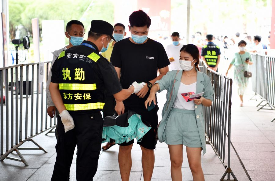 A security guard takes temperature of visitors during the 17th Hainan International Auto Exhibition in Haikou, south China's Hainan Province, May 22, 2020. /Xinhua