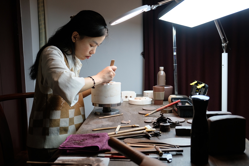 A young artist concentrates on making a purple clay teapot at the Yucheng Kiln Cultural Research Institute in Ningbo, Zhejiang. /CFP